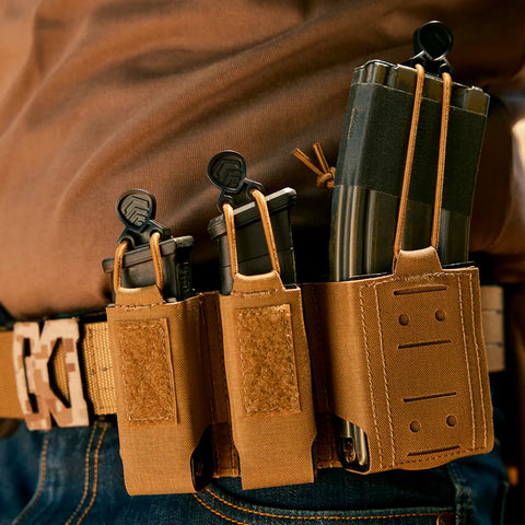 Three magazine pouches attached to a belt with a person wearing brown pants in the background.