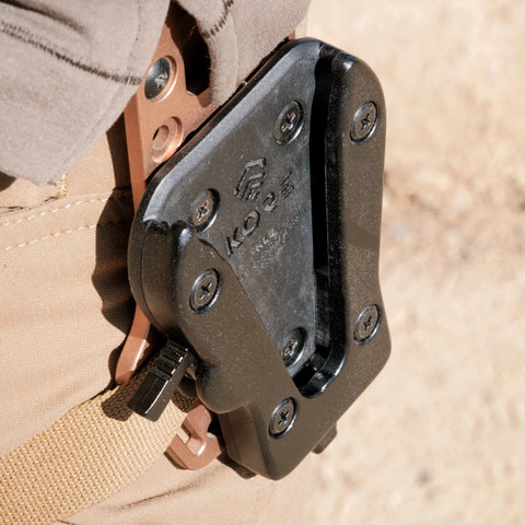 Close-up of a tactical knife sheath attached to a beige jacket.