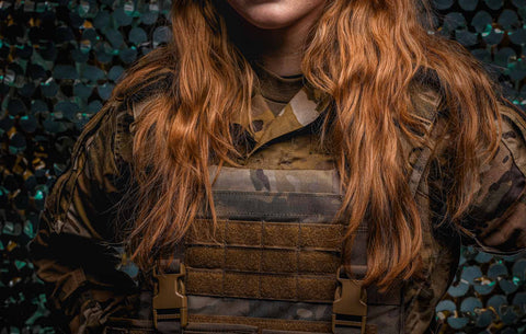 Female soldier wearing a modern tactical vest in camouflage, equipped with light body armor for personal protection in an outdoor setting.