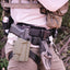 Person wearing tactical gear with a gun holster and gloves on a blurred natural background
