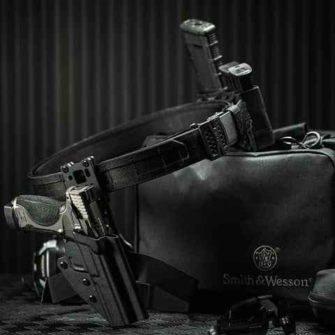 Kore Black belt with a gun holster and Smith & Wesson firearm against a dark background