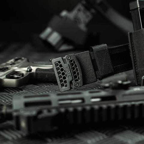 Close-up of tactical Kore battle belt including a gun and magazine on a dark surface.