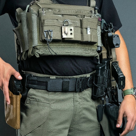 Person wearing tactical gear with a focus on a green utility belt and pouches.